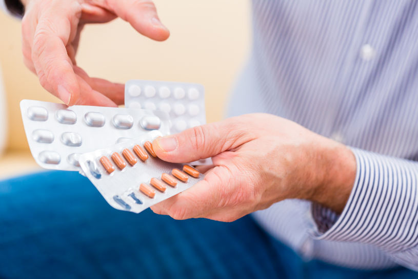 A man holds different pills in his hand.