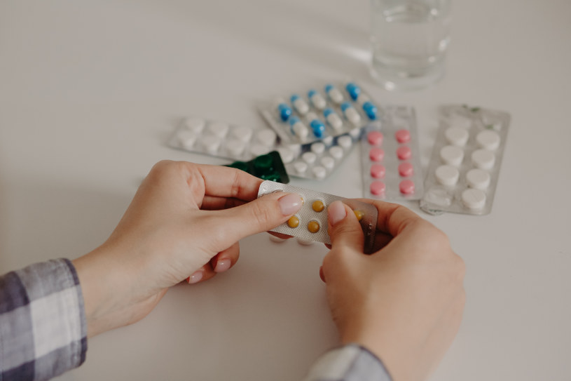 A woman holds different pills and capsules.