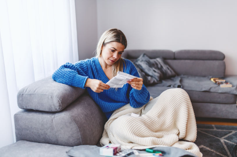 A woman on sofa reads about Methocarbamol side effects.