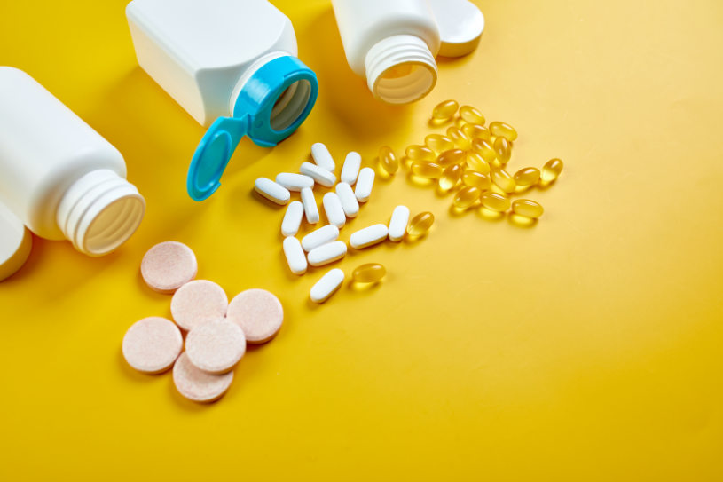 Different pills and capsules are on the yellow background.