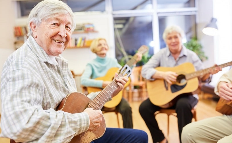 Elderly people playing guitars as a form of music therapy.