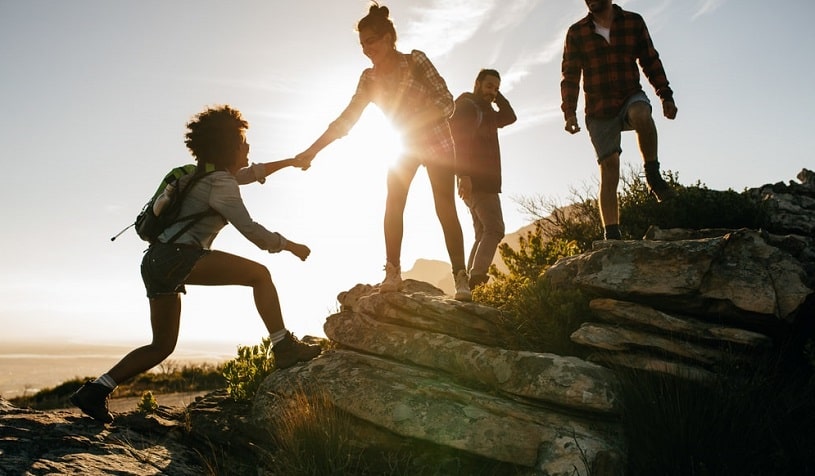 People helping each other climb the hill.