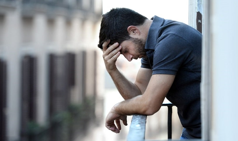 Depressed man standing outdoors.