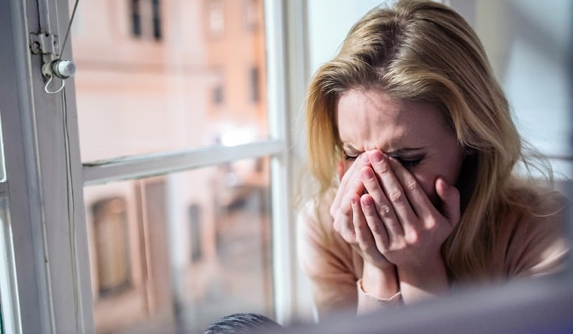 Woman sitting at the window crying.