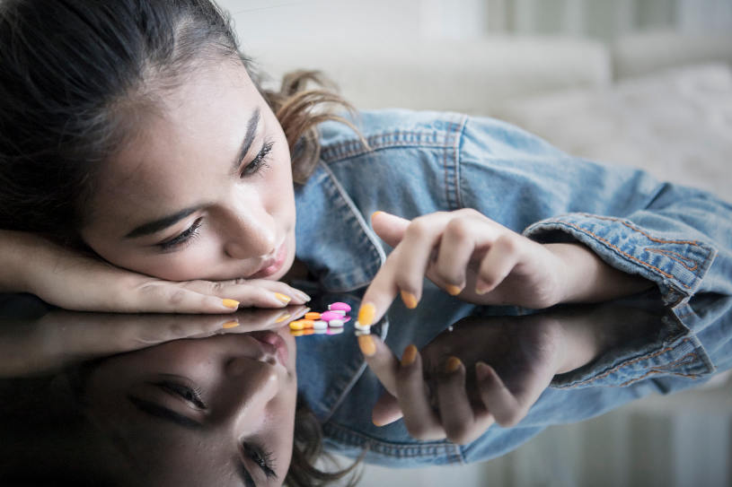 A depressed woman looks at Remeron pills and experiences Remeron withdrawal symptoms.