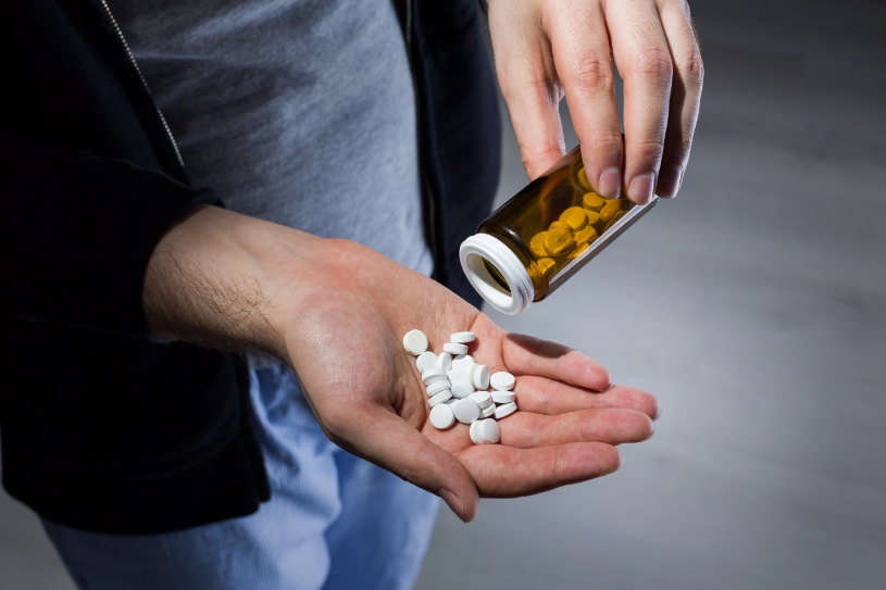 A man pours Tazodone pills in his hand.