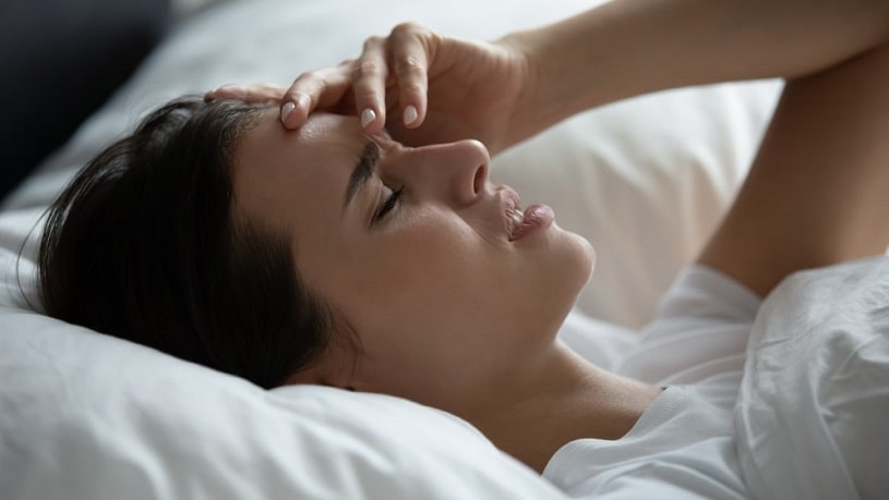 Woman experiencing withdrawal lying in bed.