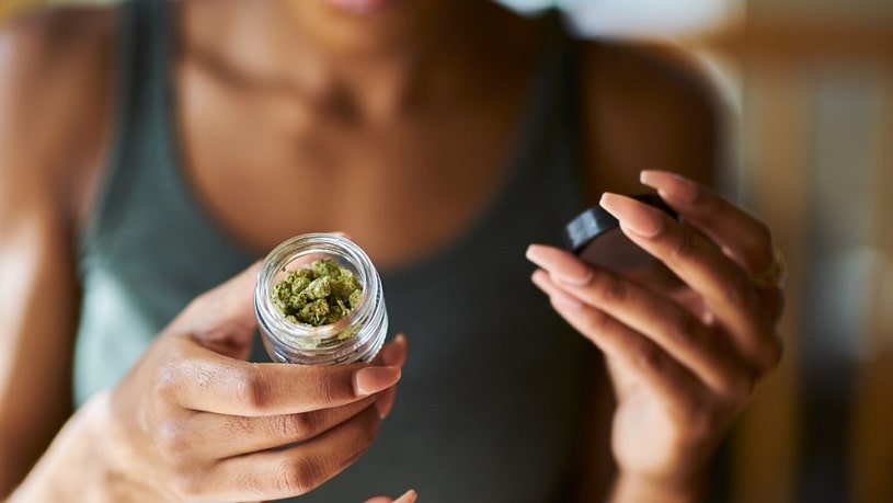 Woman holding medicinal marijuana in the bottle.