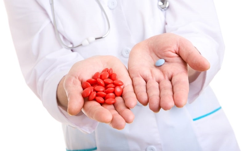 Doctor holding pills offering them to the patient.