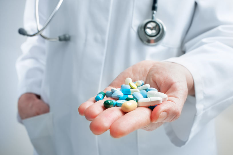 A doctor holds different pills in his hand.