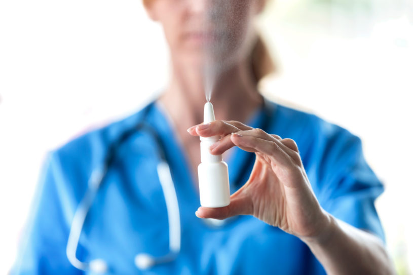 A medical worker holds nasal spray in her hand over white background.