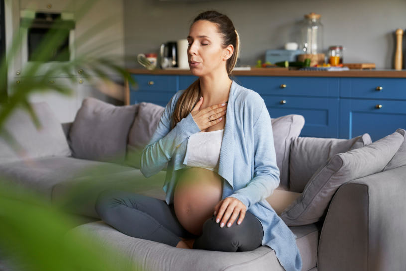 A pregnant woman sits on sofa and experiences some side effects because of inhalants misuse.