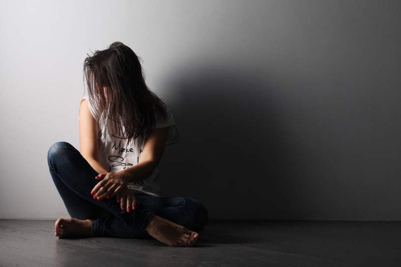 A teenage girl is sitting on the ground and suffering from whippets side effects.