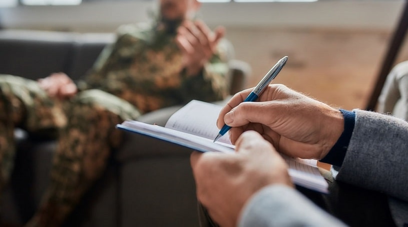 Psychologist making notes about a veteran having PTSD and addiction.