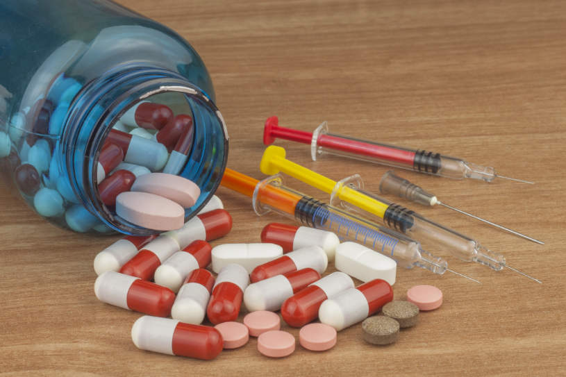 Different anabolic-steroids pills and syringes on the table.