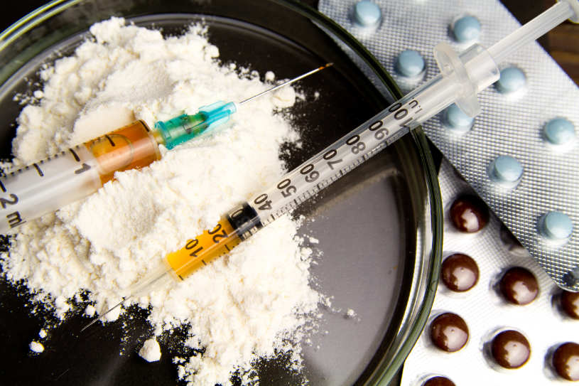 Different pills and syringe on the table.