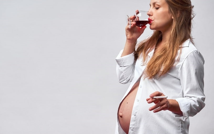 Pregnant woman smoking and drinking wine.