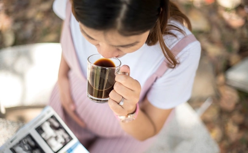 Pregnant woman drinking a cup of coffee.