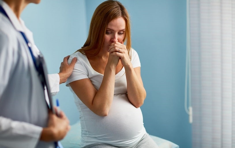 Worried pregnant woman talking to a doctor.