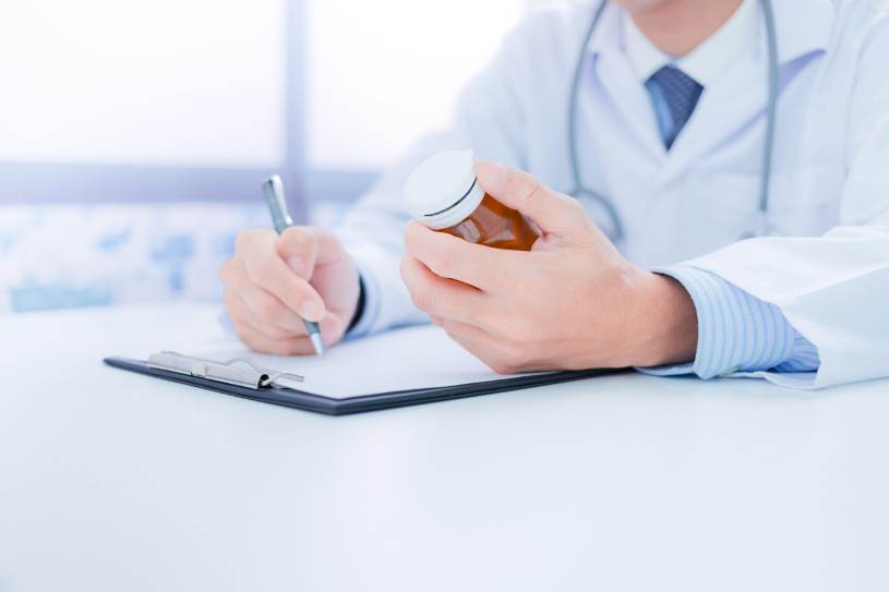 A doctor holds buspar pills and writes something.