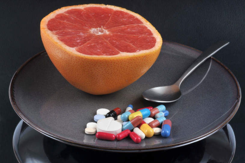 A grapefruit and some pills on the table.