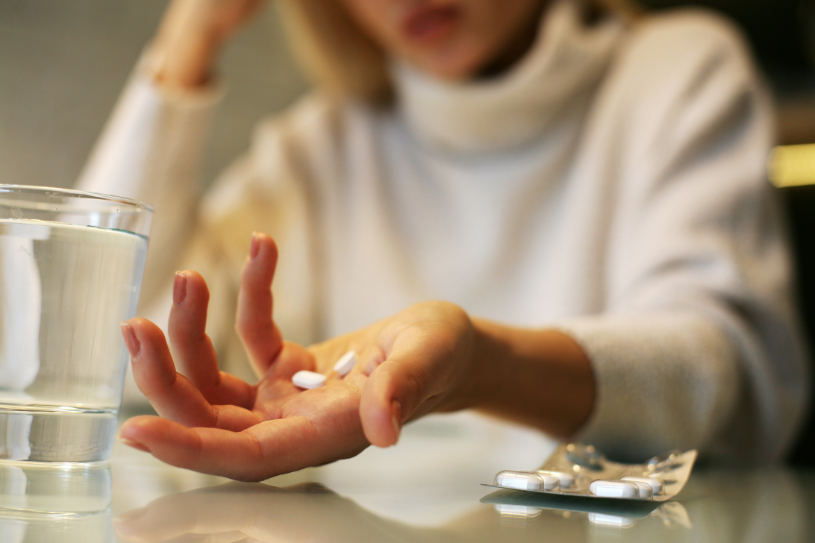 A woman experiencing paxil withdrawal symptoms holds paxil pills in her hand.