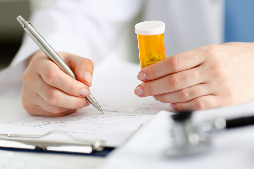A doctor writes prescription and holds a bottle of antidepressant pills.