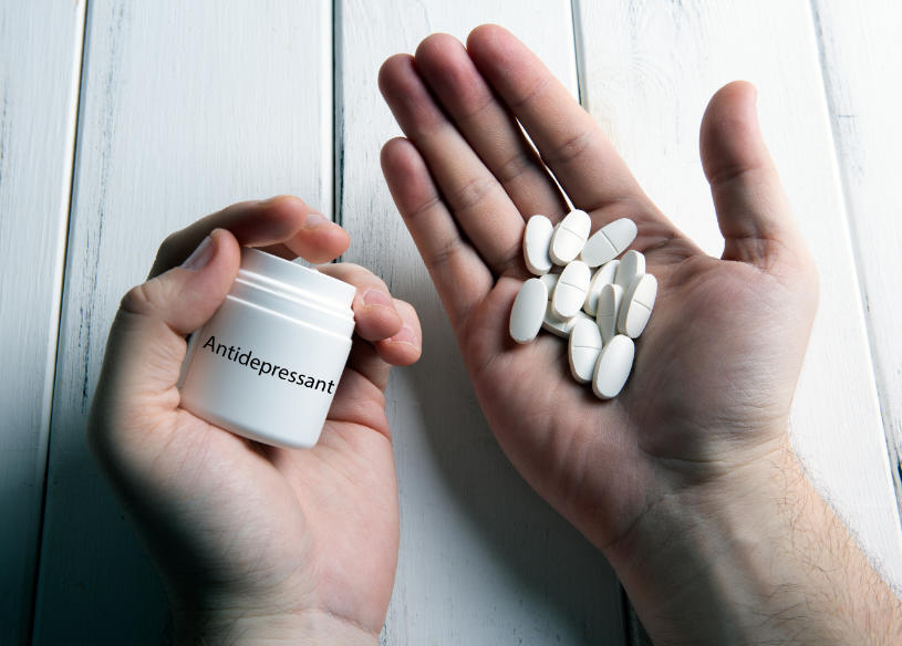 A man holds a bottle of antidepressant pills.