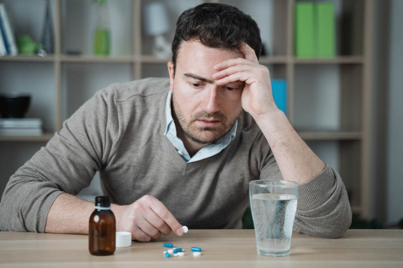 A man looks at pills on the table.