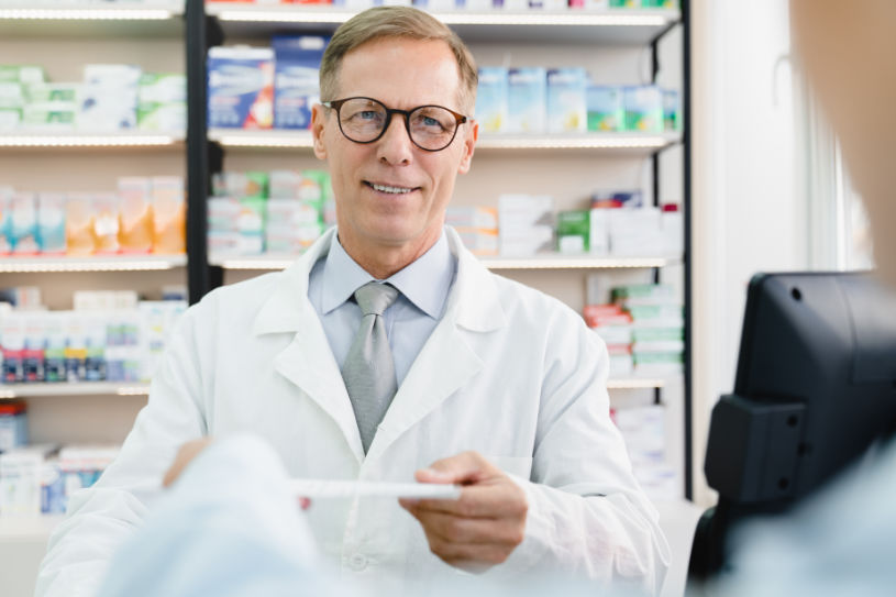 A pharmacist gives some pills to a person.