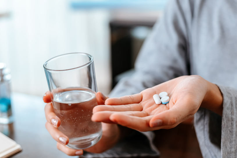 A woman holds several pills in her hand.