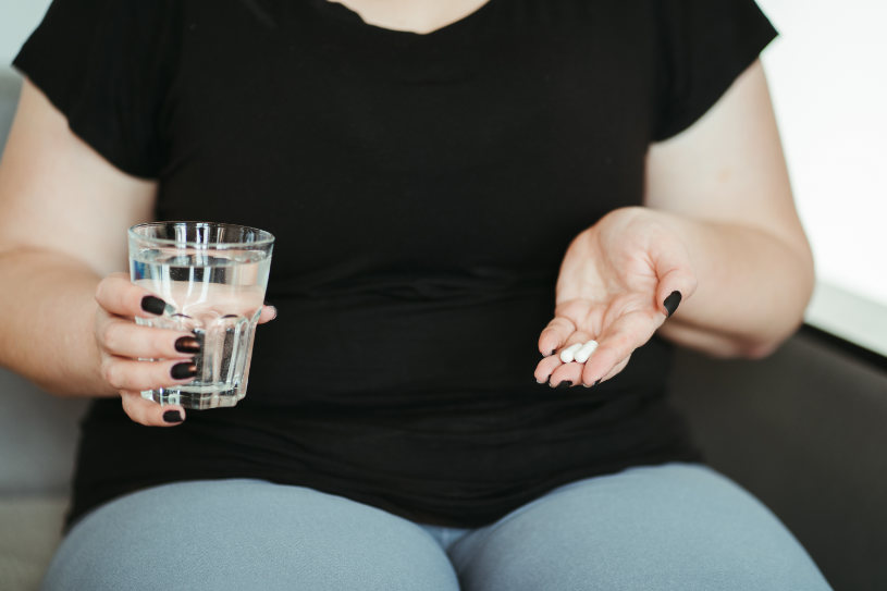 A woman with obesity looks at some pills.