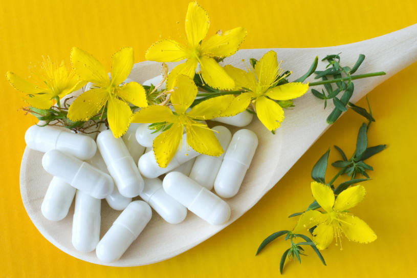 St. John's Wort flowers and antidepressant pills over the yellow background.