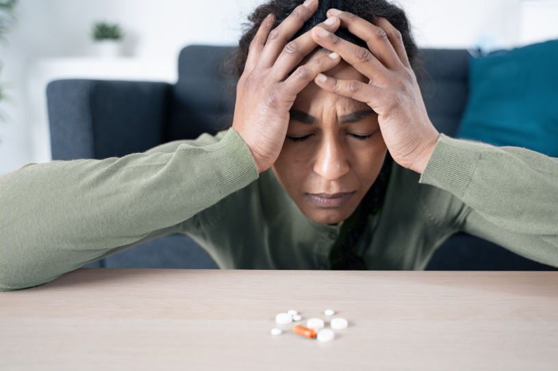 A woman addicted to benzodiazepines looks at some pills on the table.