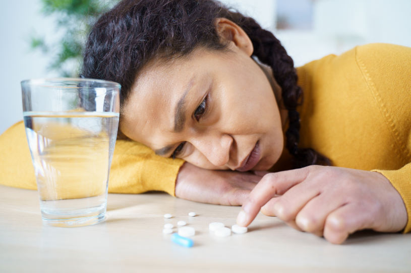 A woman experiencing benzos withdrawal symptoms looks at some pills on the table.